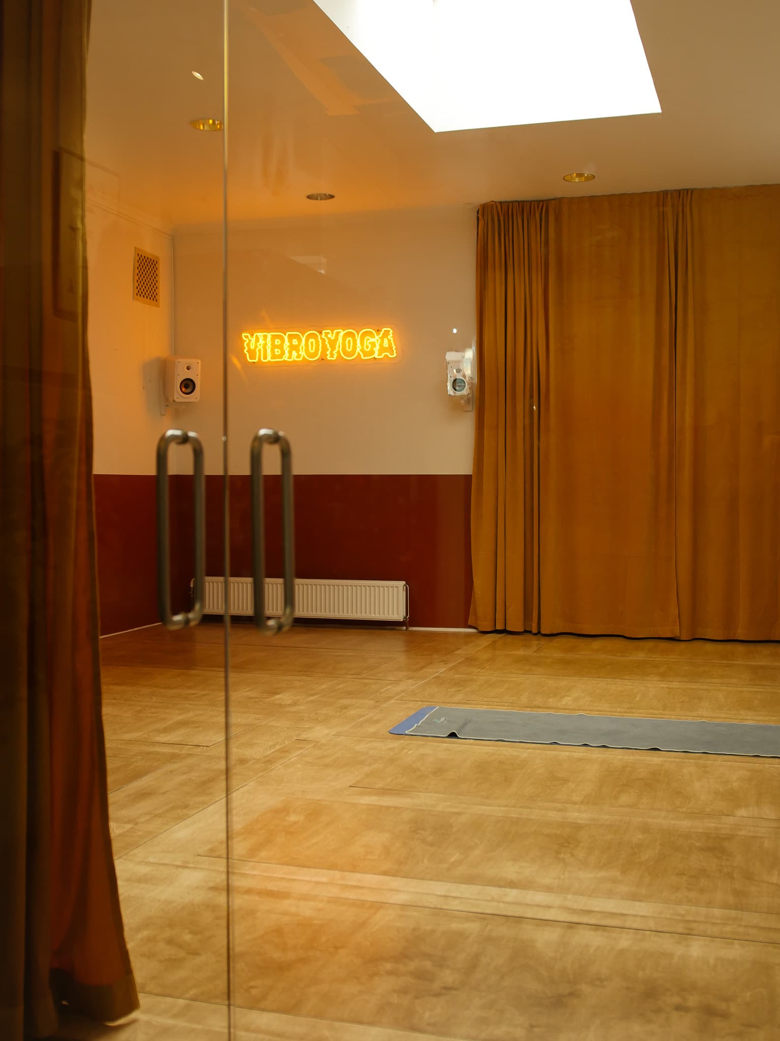 The Vibration Shower studio — a warm vibroacoustic wooden floor beneath a glowing neon sign